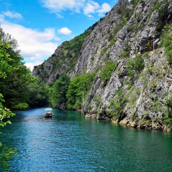 A boat on the water between the cliffs of Matka Canyon