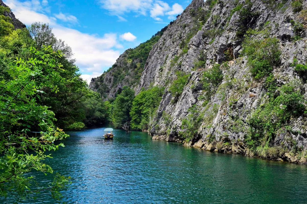 A boat on the water between the cliffs of Matka Canyon